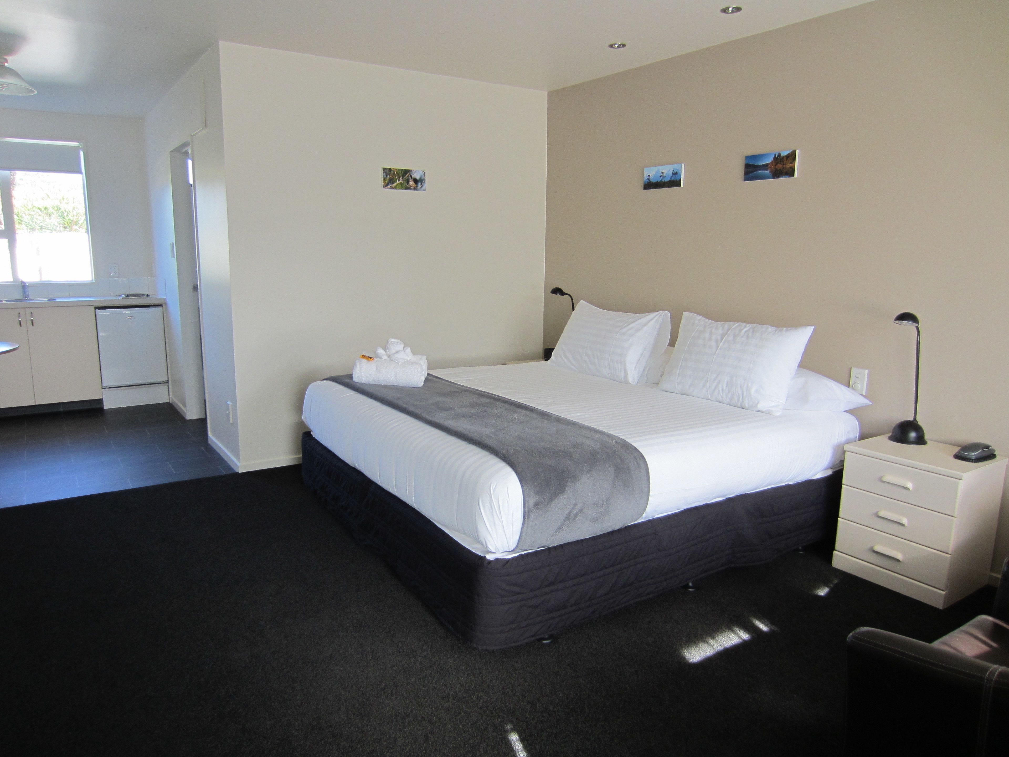 Une chambre d’hôtel avec un lit, une table de chevet et un petit bureau avec une chaise.