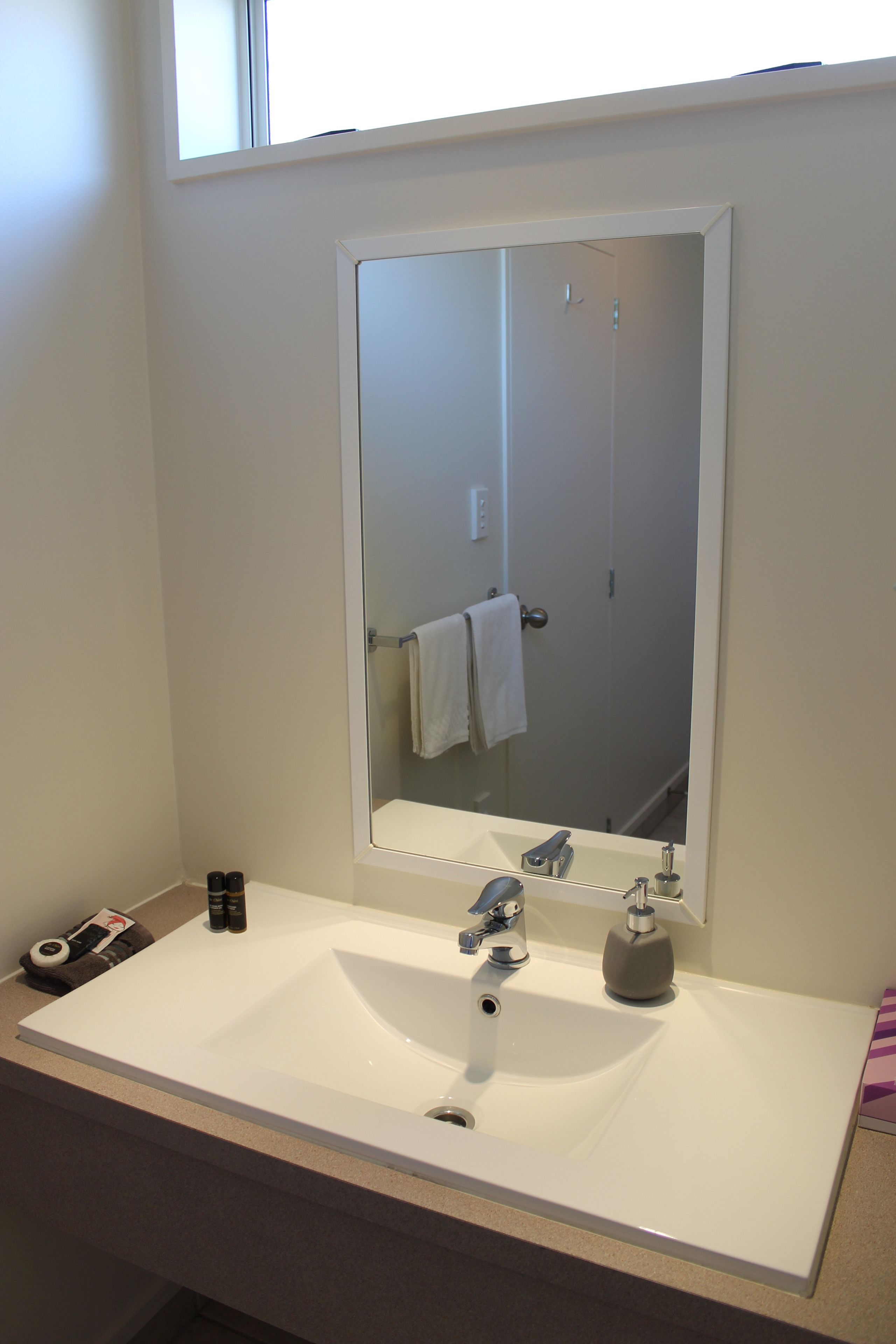 Une salle de bain avec un lavabo blanc, un miroir et un porte-serviettes.