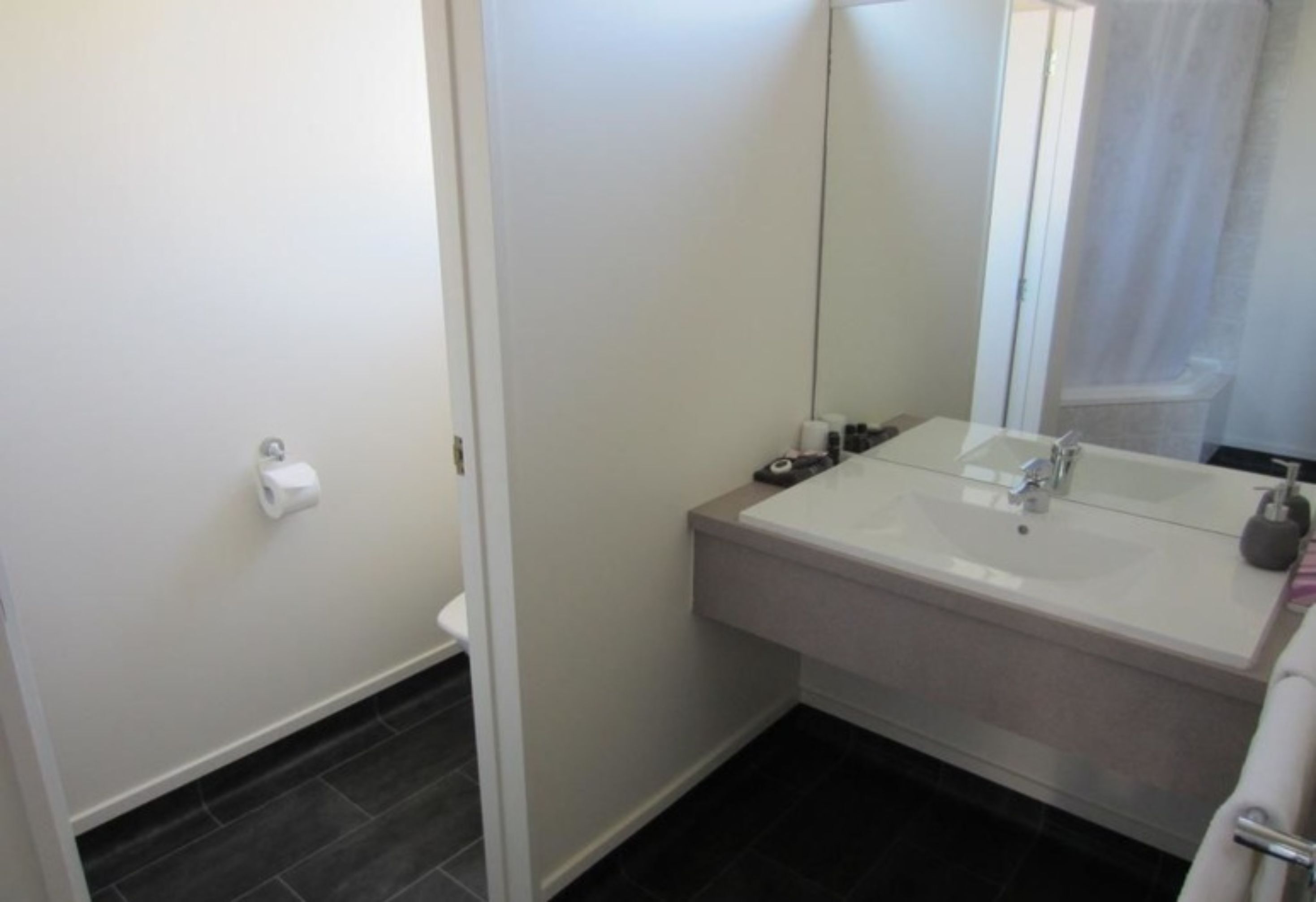Une salle de bain avec un lavabo blanc, un miroir et des toilettes.