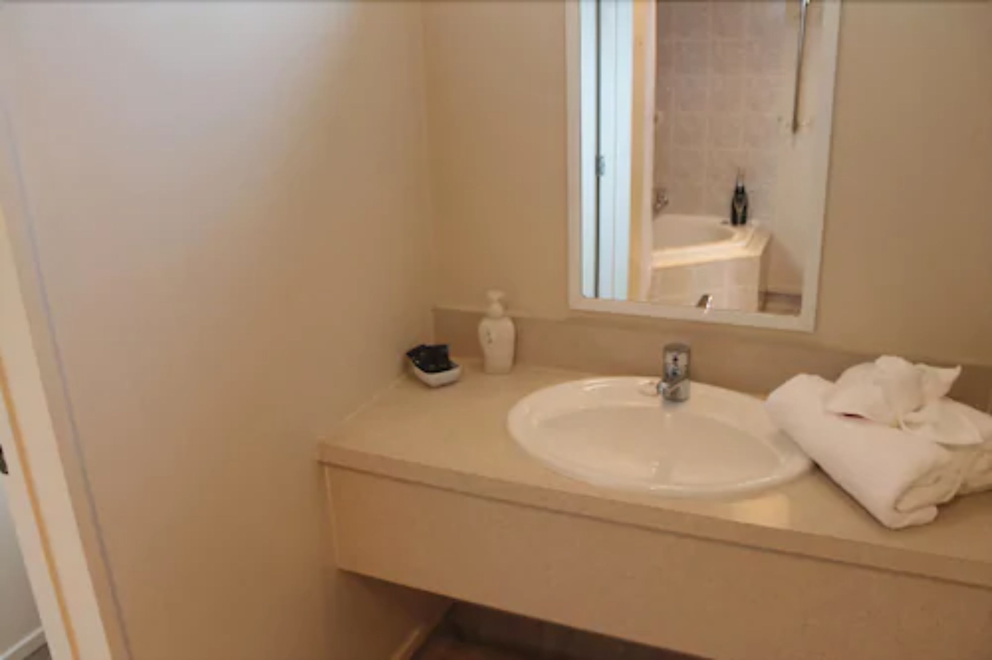 Baño con lavamanos, espejo y artículos de aseo.