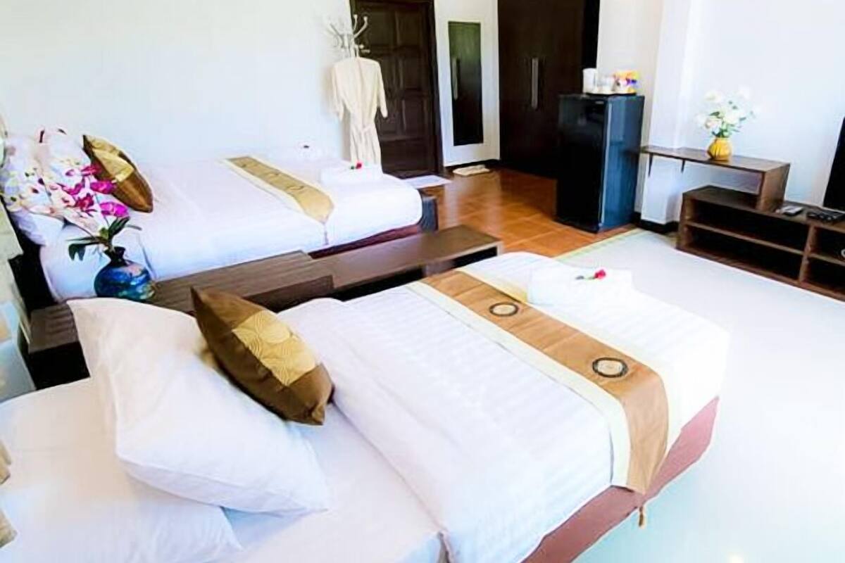 Ein Hotelzimmer mit zwei Betten, einem Schreibtisch, einem Kleiderschrank und einem Fernseher.