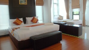 A hotel room with a large bed, a desk, and a window with curtains.