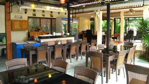 A restaurant with wicker furniture, a counter, and a view of the outdoors.