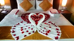 A bed with a heart-shaped arrangement of rose petals and towels. - Balairung Hotel (Jakarta)