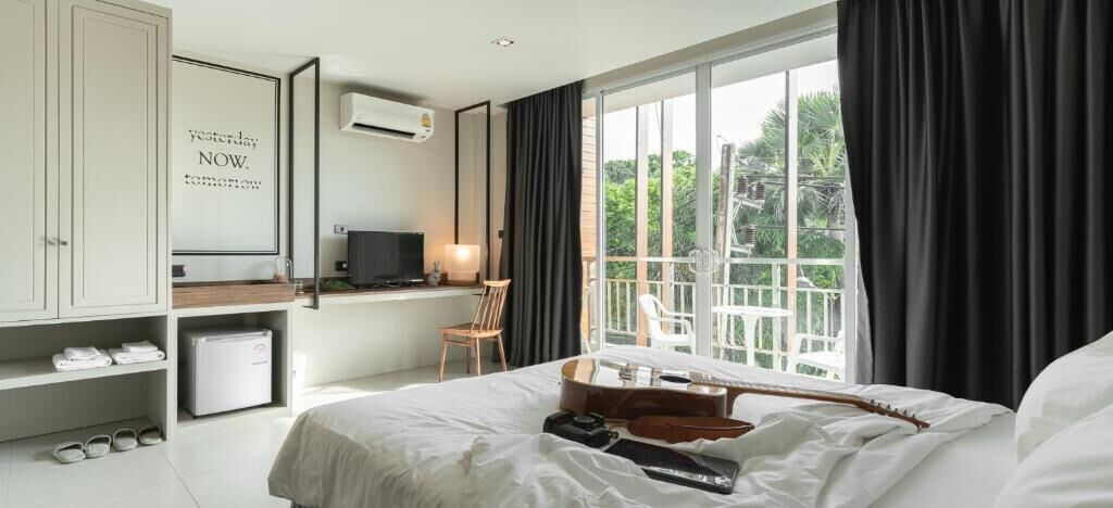 Habitación de hotel con cama, escritorio, silla, televisor y ventana con cortinas.