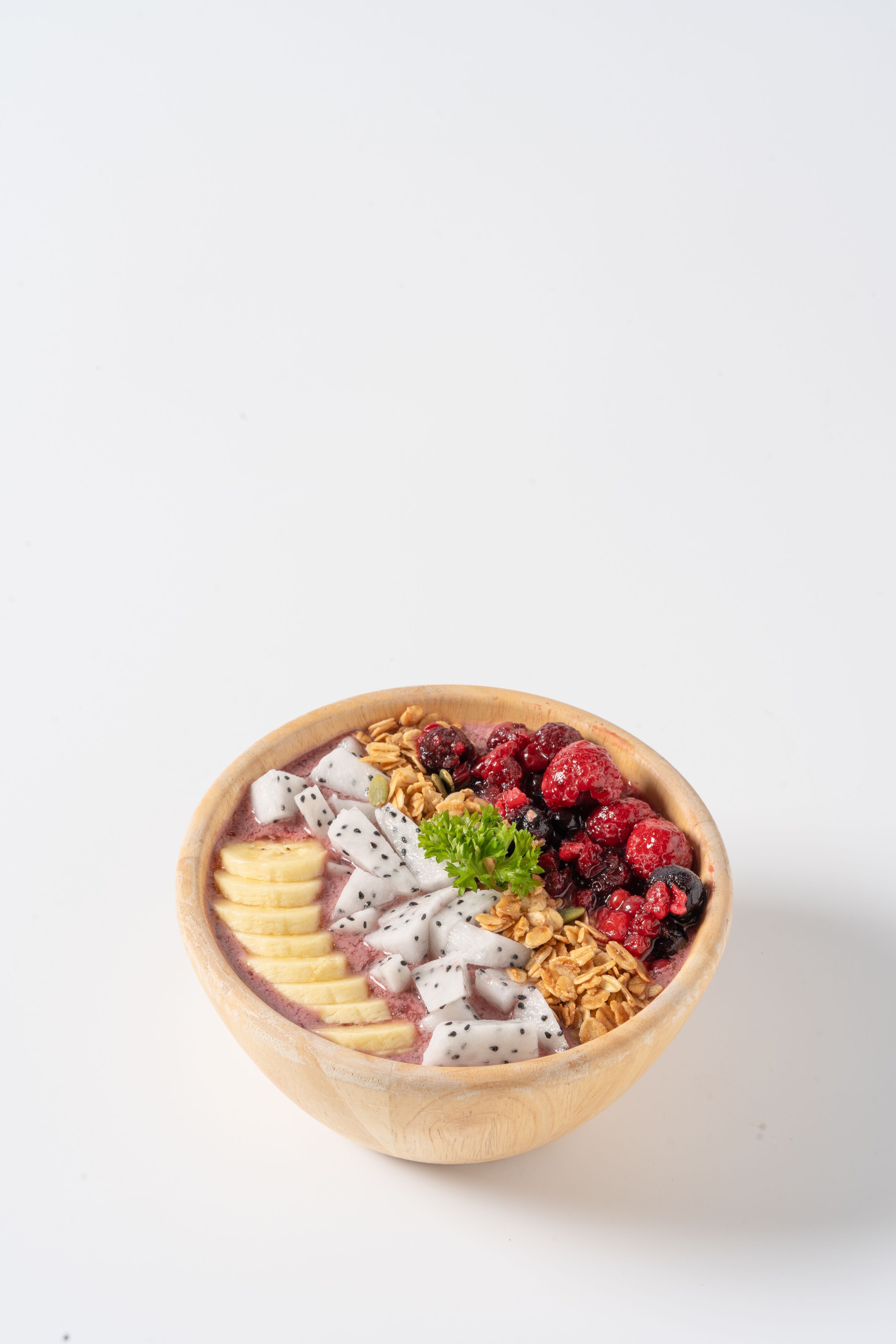 Eine Holzkreuzschale mit Obst und Granola zum Frühstück.