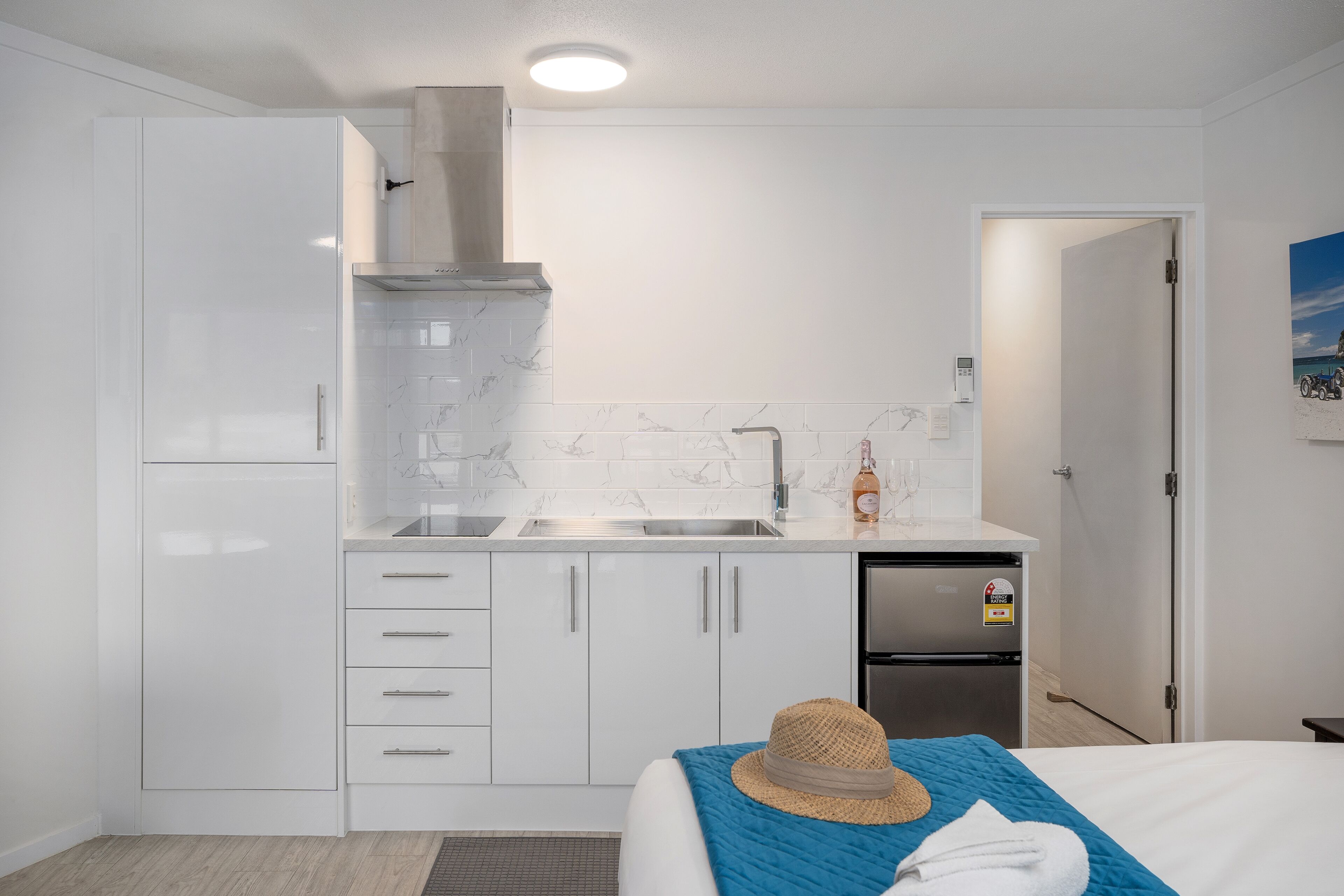 A compact kitchenette with a built-in oven, a stainless steel refrigerator, and a microwave.