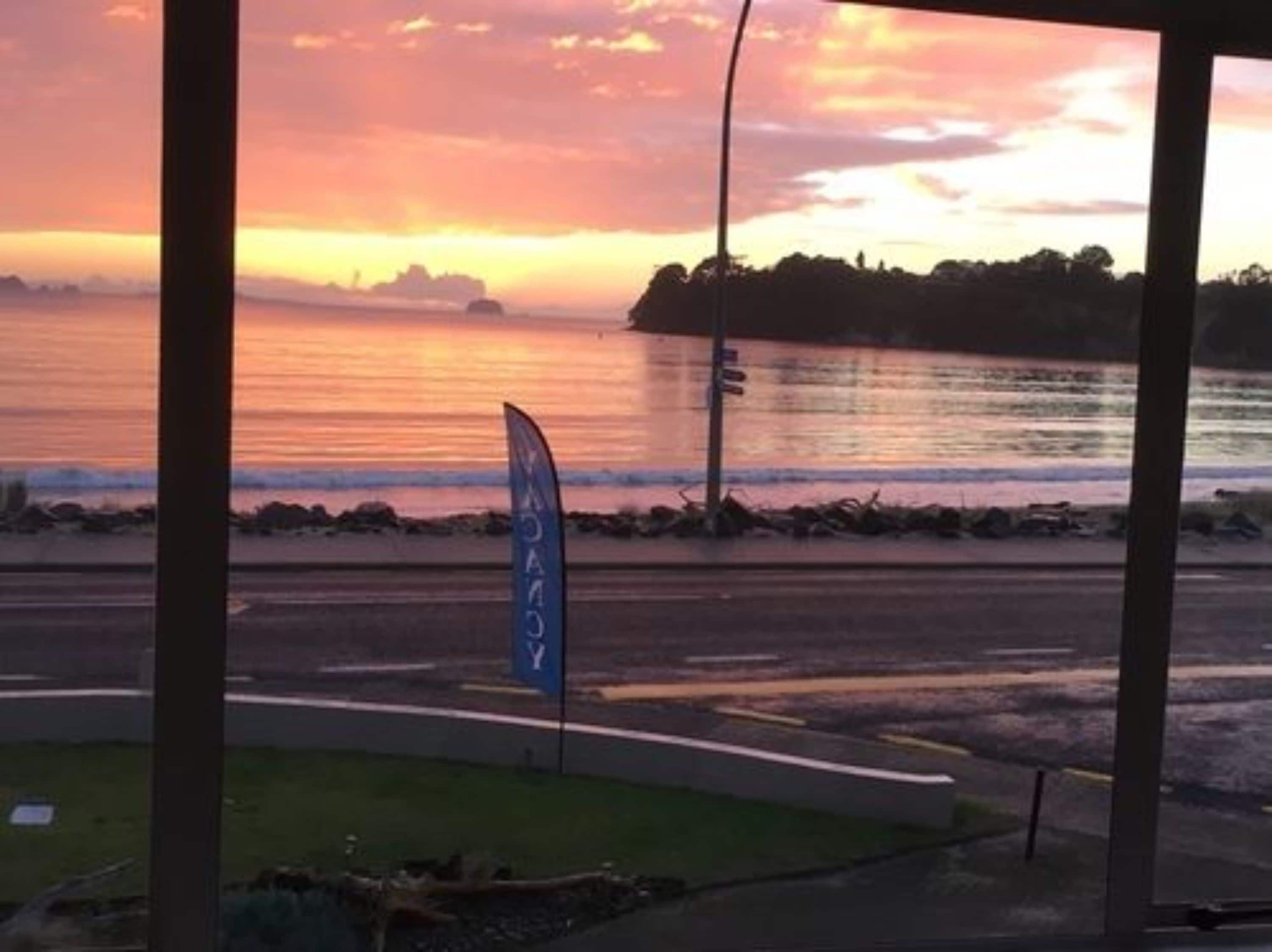 A view of a sunset over a body of water with a flag in the foreground.