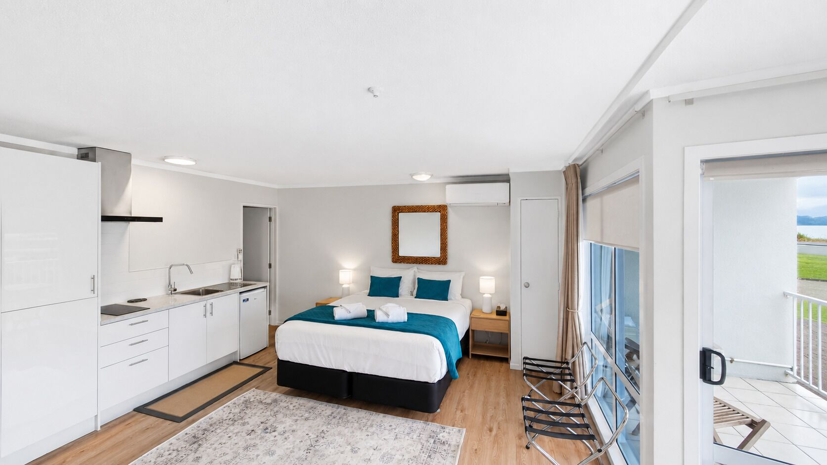 Habitación de hotel moderna con cama, mesita de noche y vistas al exterior.