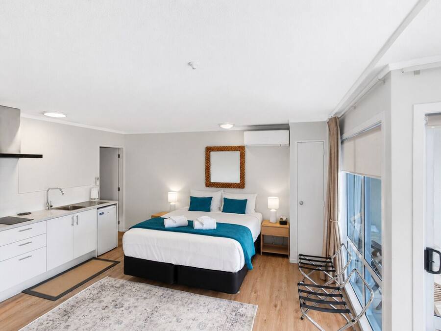 Habitación de hotel moderna con cama, mesita de noche y vistas al exterior.
