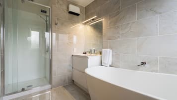 A modern bathroom with a glass-enclosed shower, a freestanding bathtub, and a vanity with a towel hanging on the wall.