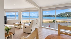 Amplia sala de estar con un ventanal que ofrece vistas a una playa y al mar.