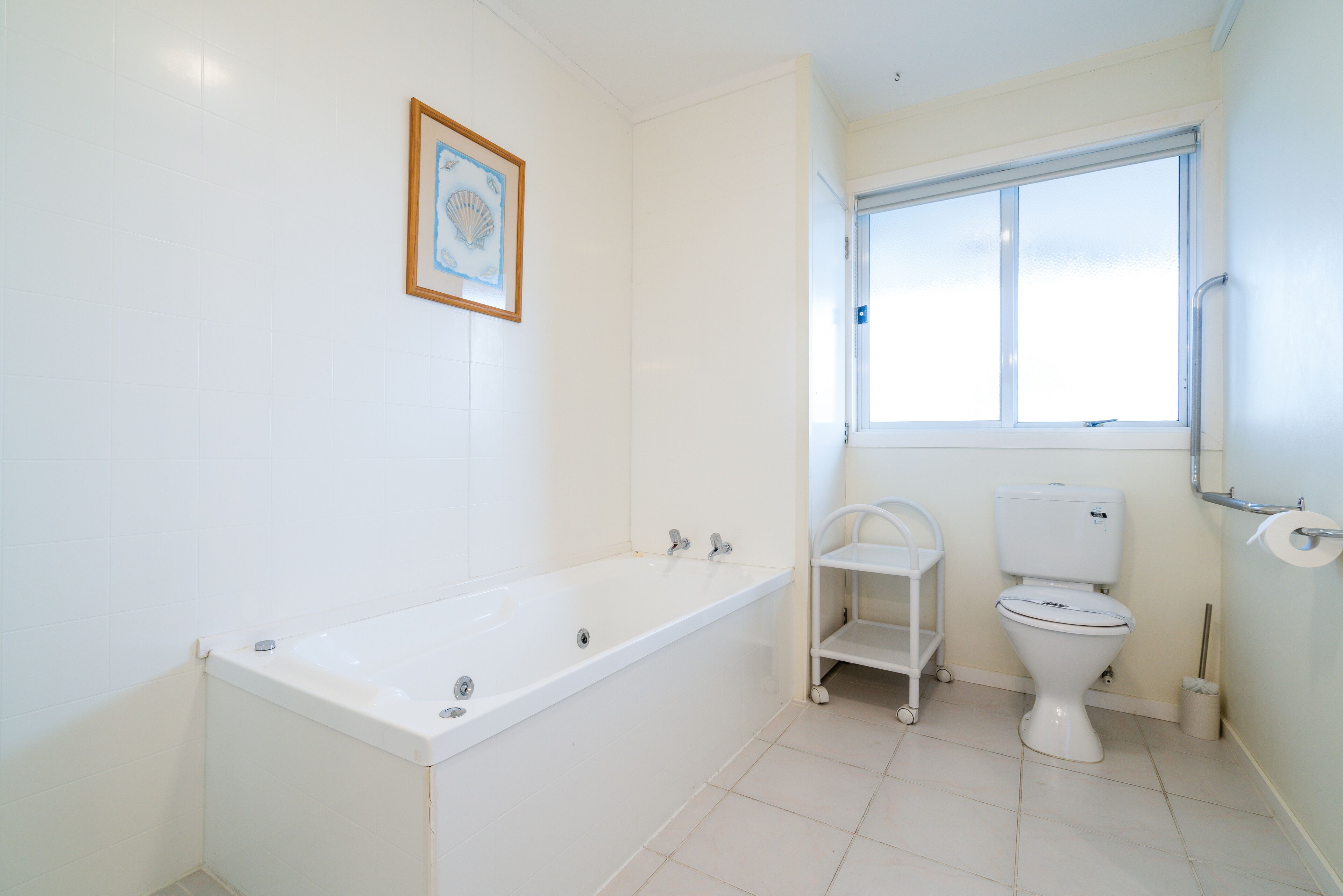 Un baño con bañera, inodoro y ventana.