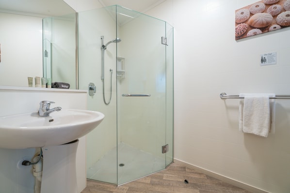 Une salle de bain moderne avec une douche à parois de verre, un lavabo blanc et un porte-serviettes.