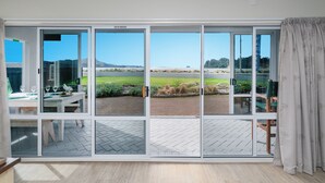 A room with a large sliding glass door leading to an outdoor area with a view of a grassy field and mountains.