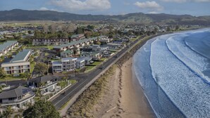 A coastal town with residential buildings, a beach, and mountains in the background.
