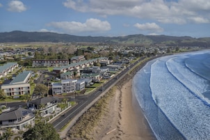 Un pueblo costero con edificios residenciales, una playa y monta ñas al fondo.
