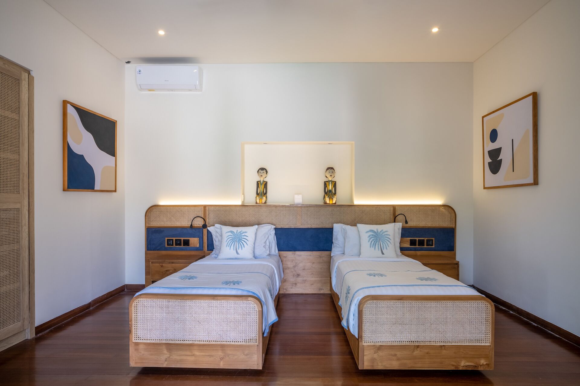 A hotel room with two single beds, a large mirror, and wall-mounted artwork.
