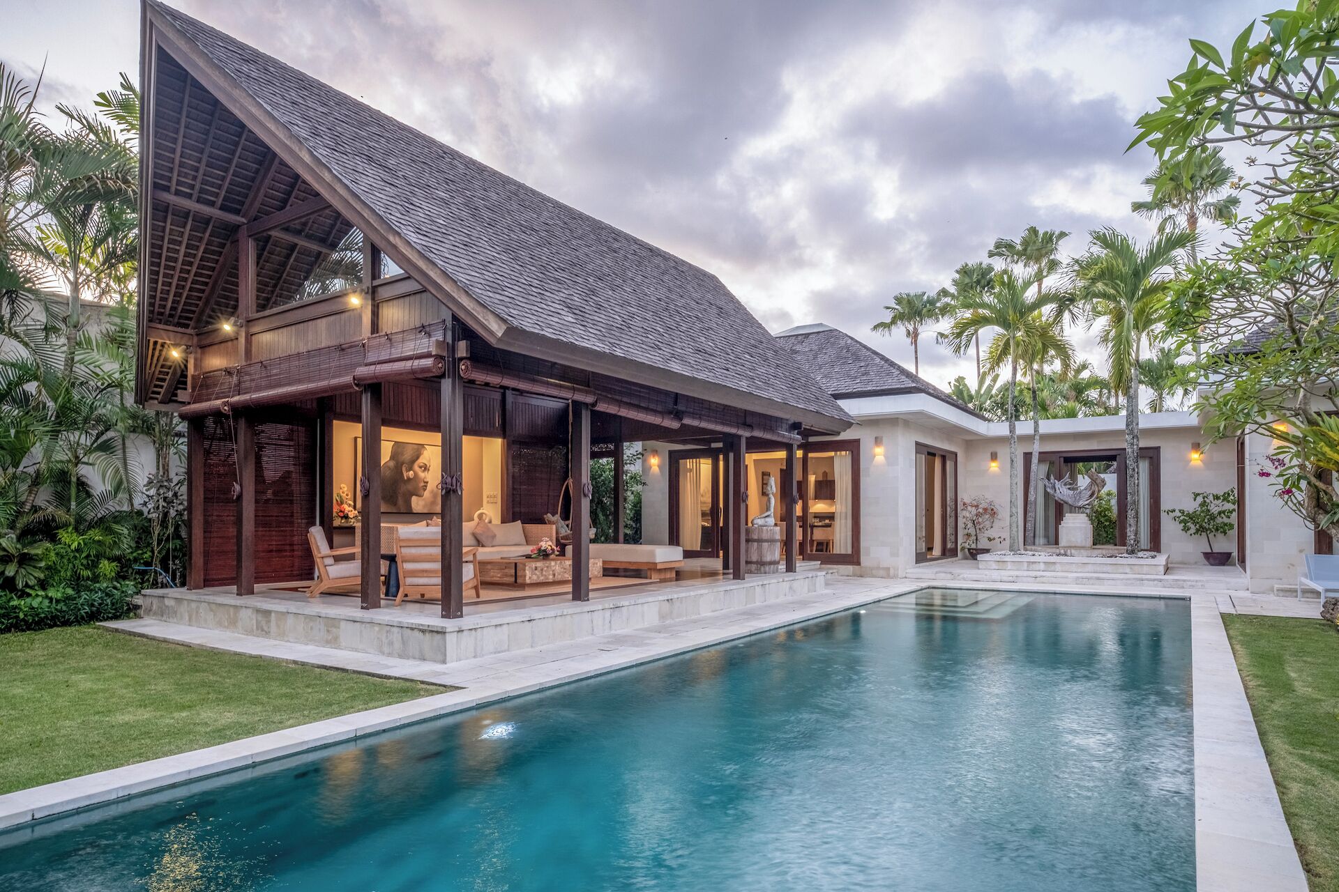 A modern house with a swimming pool, covered outdoor seating area, and lush greenery.