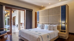 A spacious bedroom with a large bed, a wooden headboard, and a view of an outdoor area.