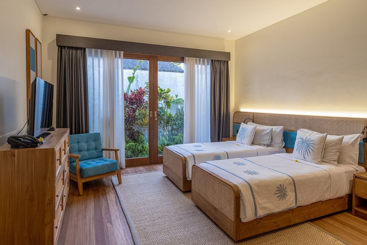A hotel room with two beds, a TV, a desk, and a chair.