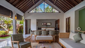 A spacious living area with a high ceiling, a dining table, and a sofa.
