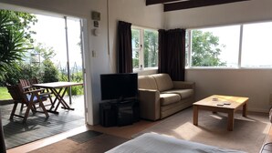 Una habitación con cama, sofá, televisor, mesa de centro y zona de comedor con sillas y mesa.