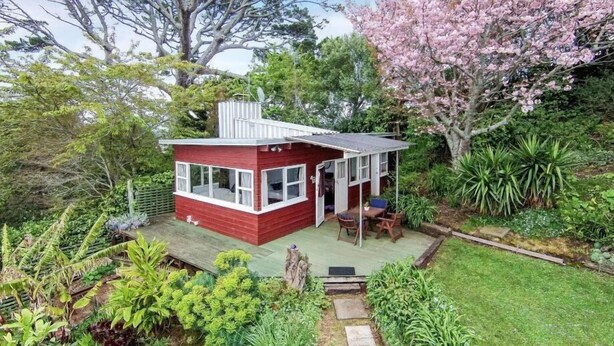 Una casa roja con un pequeño porche y un jardín.