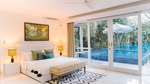 Quarto com uma cama grande, duas luminárias de cabeceira, ventilador de teto e vista para uma piscina através de grandes portas de correr.