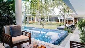 Uma área de estar à beira da piscina, com vista para a piscina e jardim.