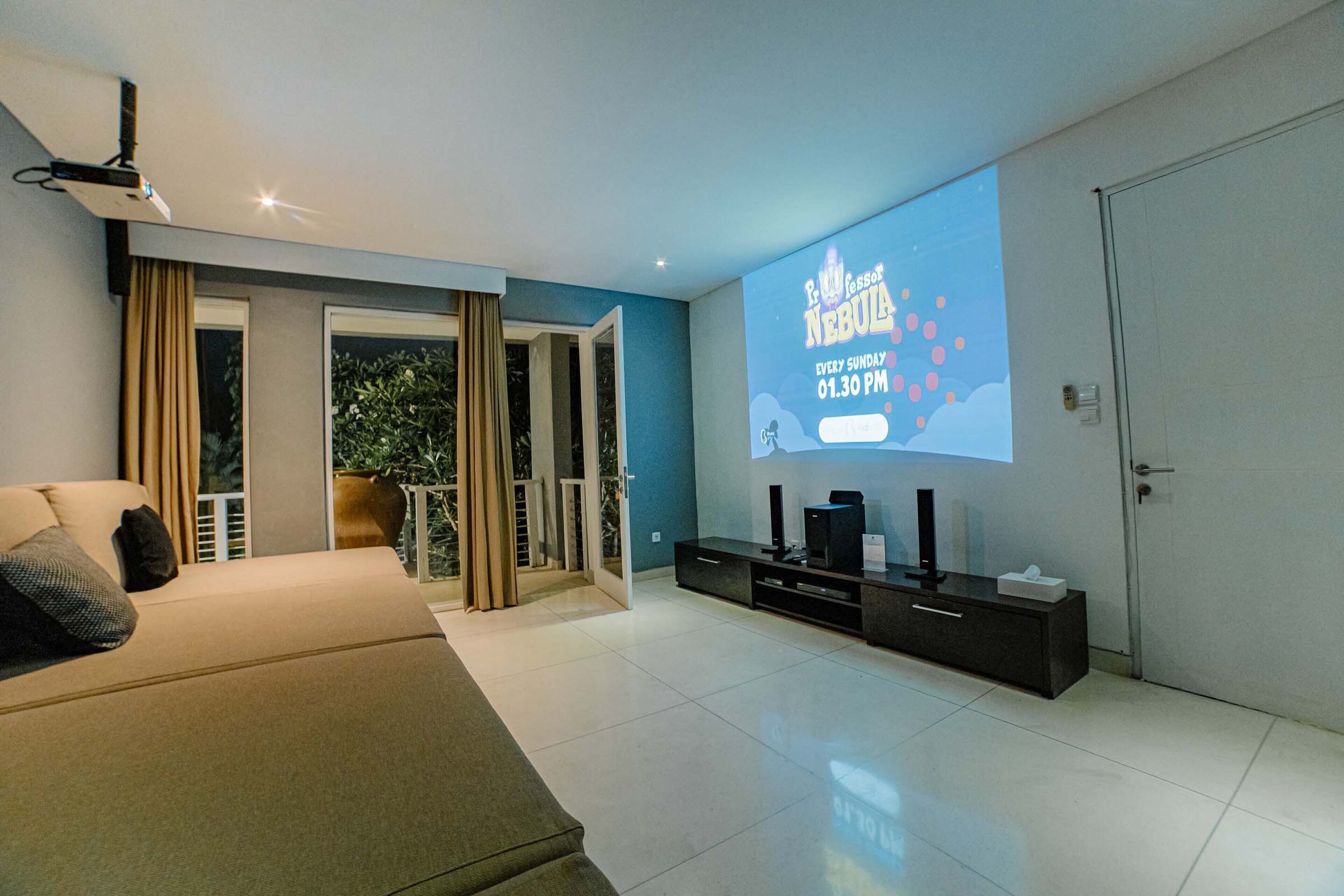 Un salon moderne doté d’un grand écran affichant le titre d’un film, d’un canapé, d’un meuble pour télévision et d’une porte-fenêtre coulissante donnant sur un balcon.