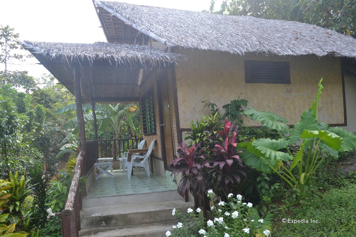 Ein reetgedecktes Haus mit Veranda, Treppe und Außenbereich mit Sitzgelegenheiten.