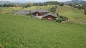 A rural property with a large house and a barn, surrounded by rolling hills and fields.