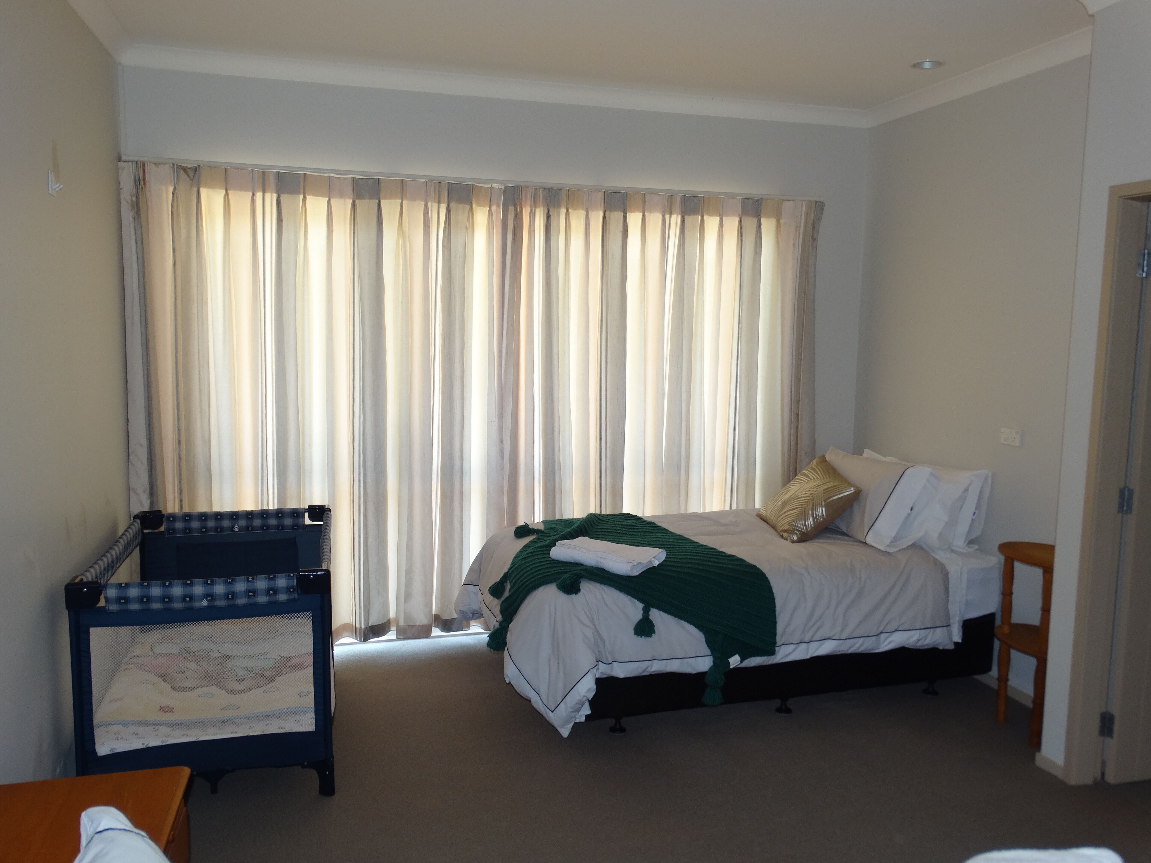 Un dormitorio con cama, un escritorio pequeño y una ventana con cortinas.