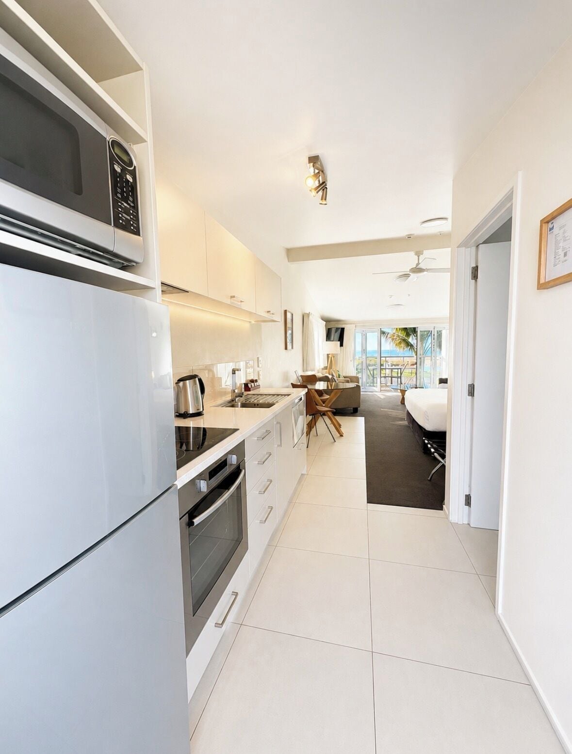 A modern kitchen with a built-in oven, a coffee machine, and a dining area with a table and chairs.