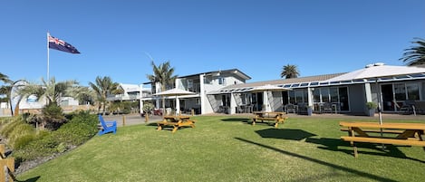 Un hotel con terraza, una bandera y palmeras.