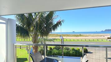 Enjoy a tranquil ocean view from this balcony, featuring a dining area with a glass table and chairs.