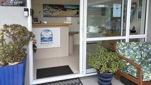 Ein Empfangsbereich mit einem Schild, das "Baileys at the Beach" zeigt, einem Computer und einer Zimmerpflanze.