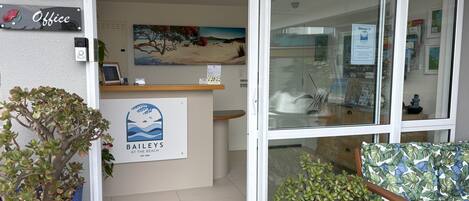 Un área de recepción con un letrero que dice "Baileys at the Beach", una computadora y una planta en maceta.