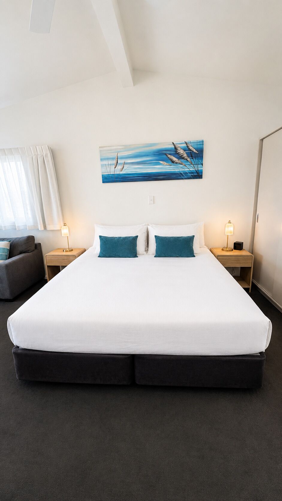 A hotel room with a large bed, two bedside tables, a desk, and a chair.