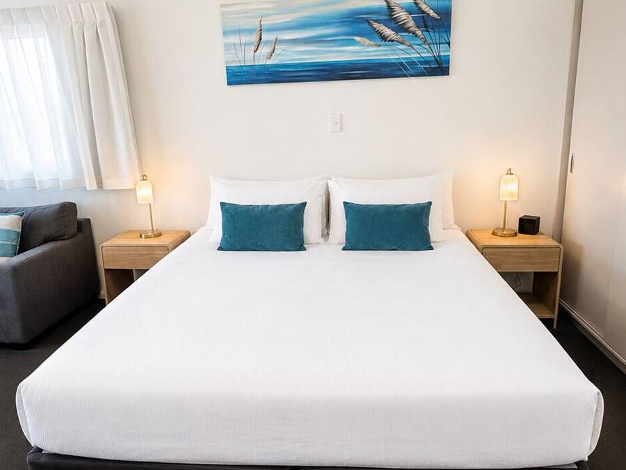 A hotel room with a large bed, two bedside tables, a desk, and a chair.