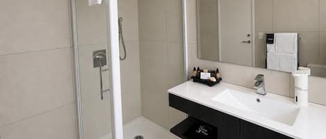 A modern bathroom with a glass-enclosed shower, a white sink, and a large mirror.
