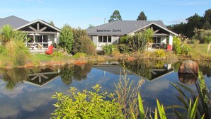 Une suite Whakapapa dotée d’une grande fenêtre, d’un bassin devant et d’un jardin avec différentes espèces de plantes.