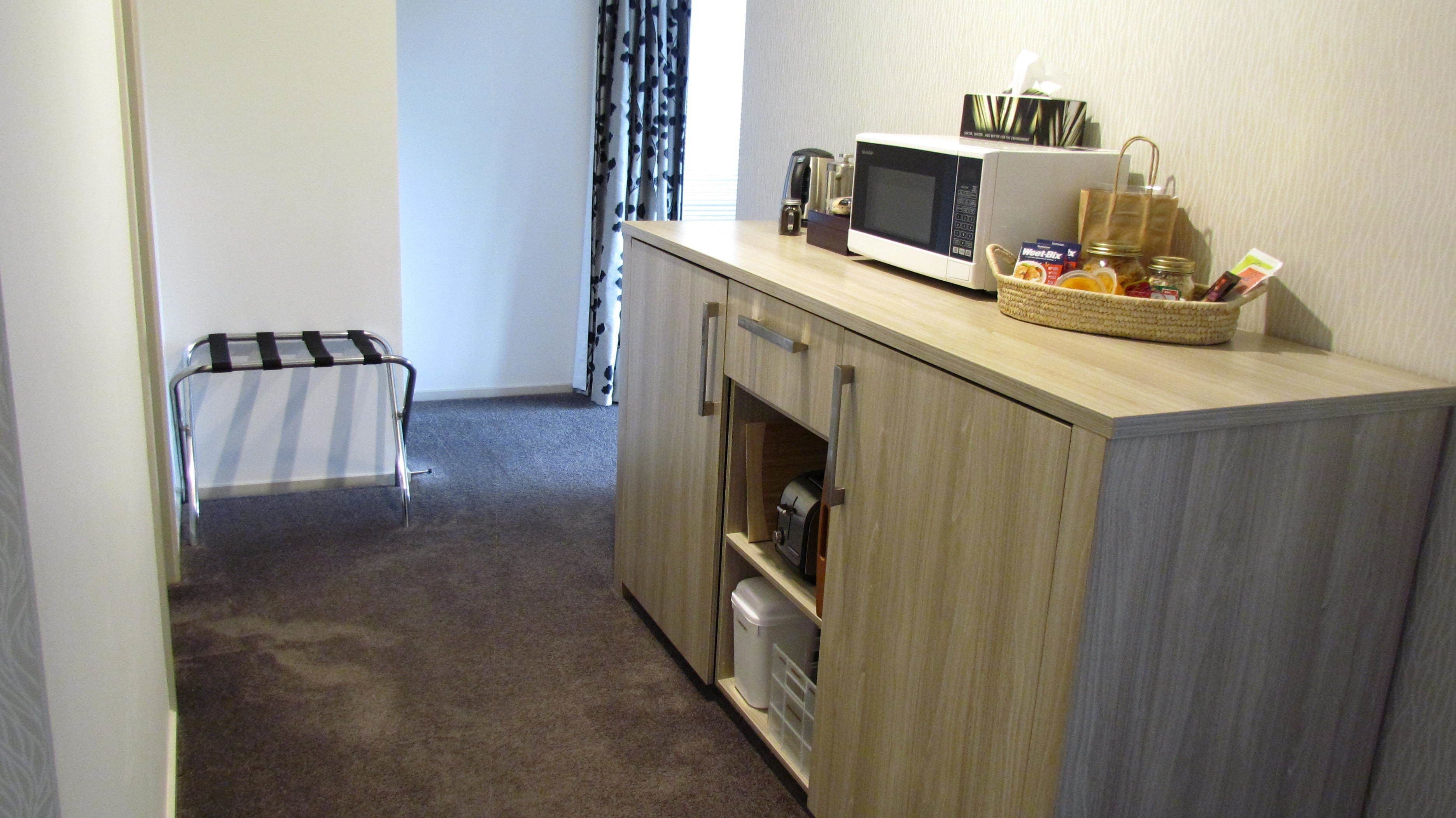 A small kitchenette with a microwave, toaster, and a basket of snacks.