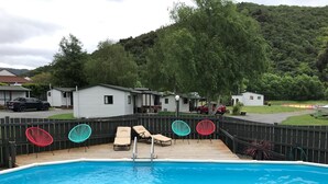 Ein Garten mit Schwimmbad, Liegestühlen und einer Holzterrasse.