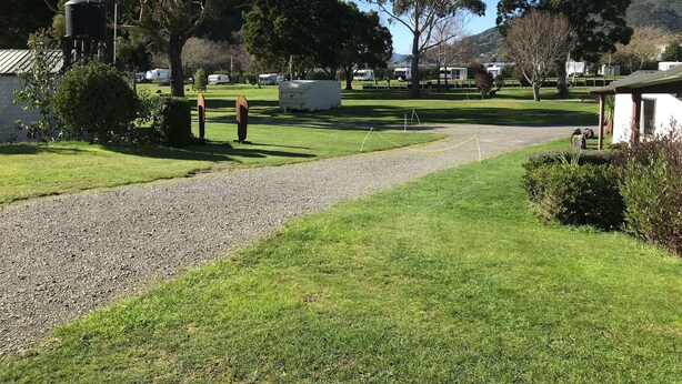 Ein Campingplatz mit Zelten, einem Kiesweg und Bäumen.
