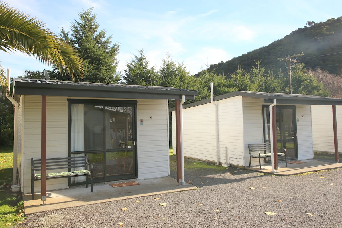 Deux petites cabanes à un seul étage, dotées de portes coulissantes en verre et de bancs à l’extérieur.