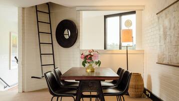 A dining area with a wooden table, black chairs, a vase with flowers, a wall-mounted clock, and a map on the wall.