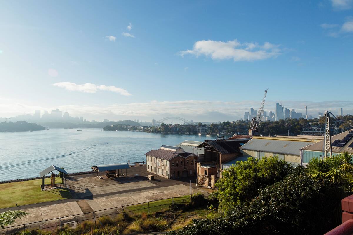 A waterfront property with a view of the city skyline, a marina, and a crane indicating construction.