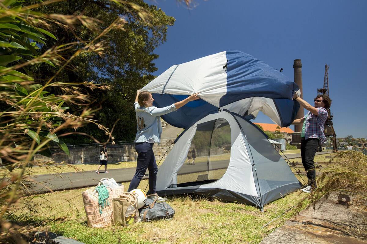 Two people setting up a tent outdoors.